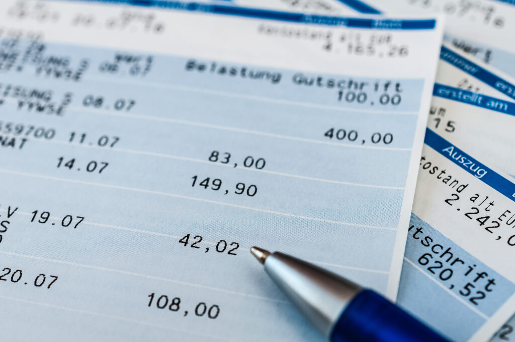 Close-up of receipts with printed numbers and a pen resting on top.