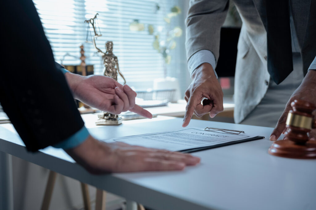 Legal professionals examining contract provisions, law office setting featuring gavel and Themis statuette